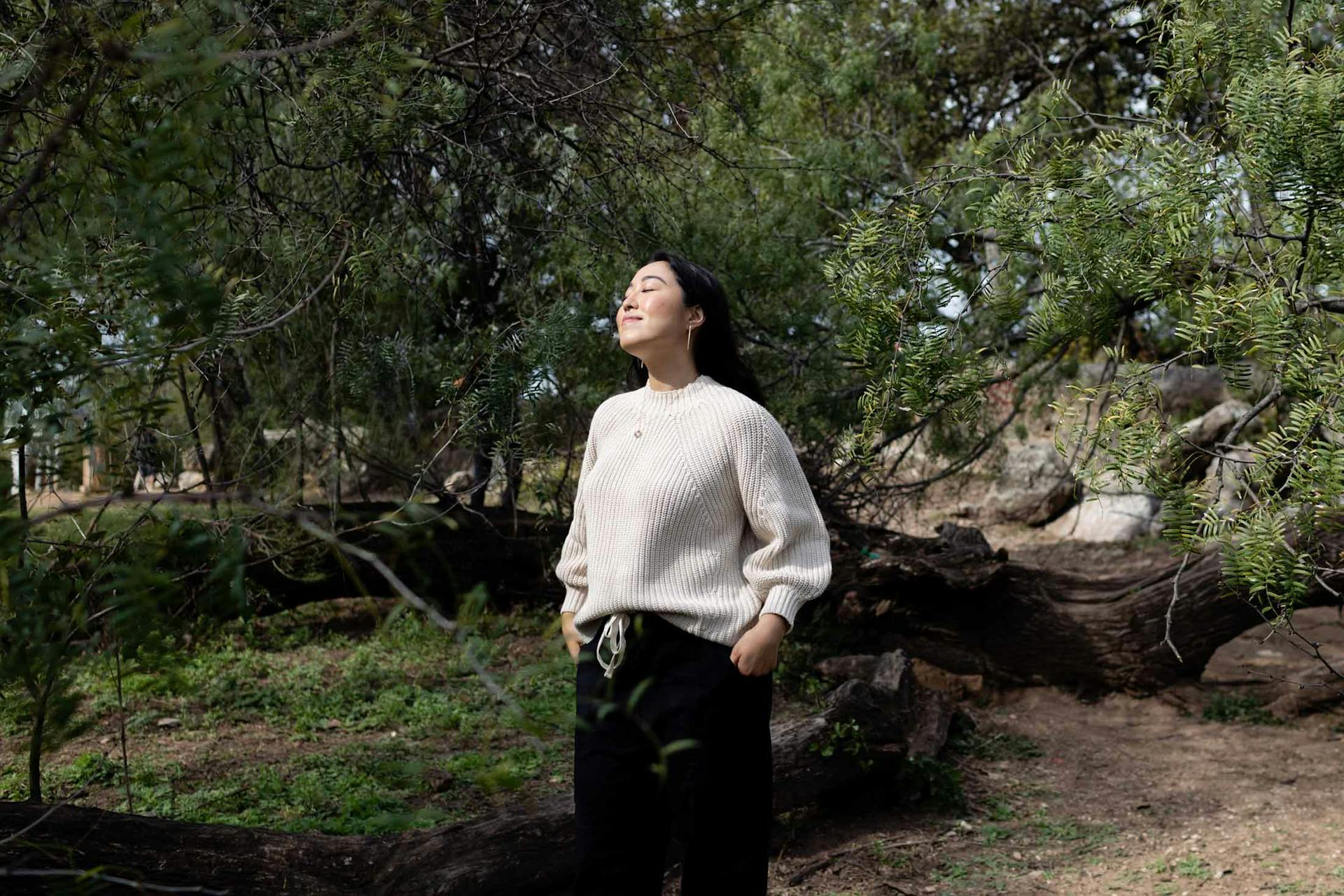 Victoria Song standing in nature wearing a light blouse and dark trousers